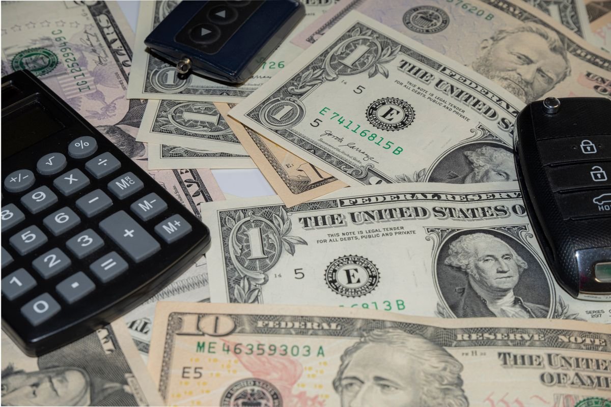 Chaves de carro sobre dinheiro e calculadora, ilustrando o cálculo de financiamento com ou sem entrada
